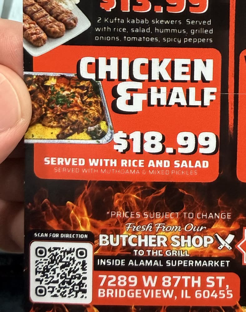 Whole charcoal chicken in a round tray over yellow rice